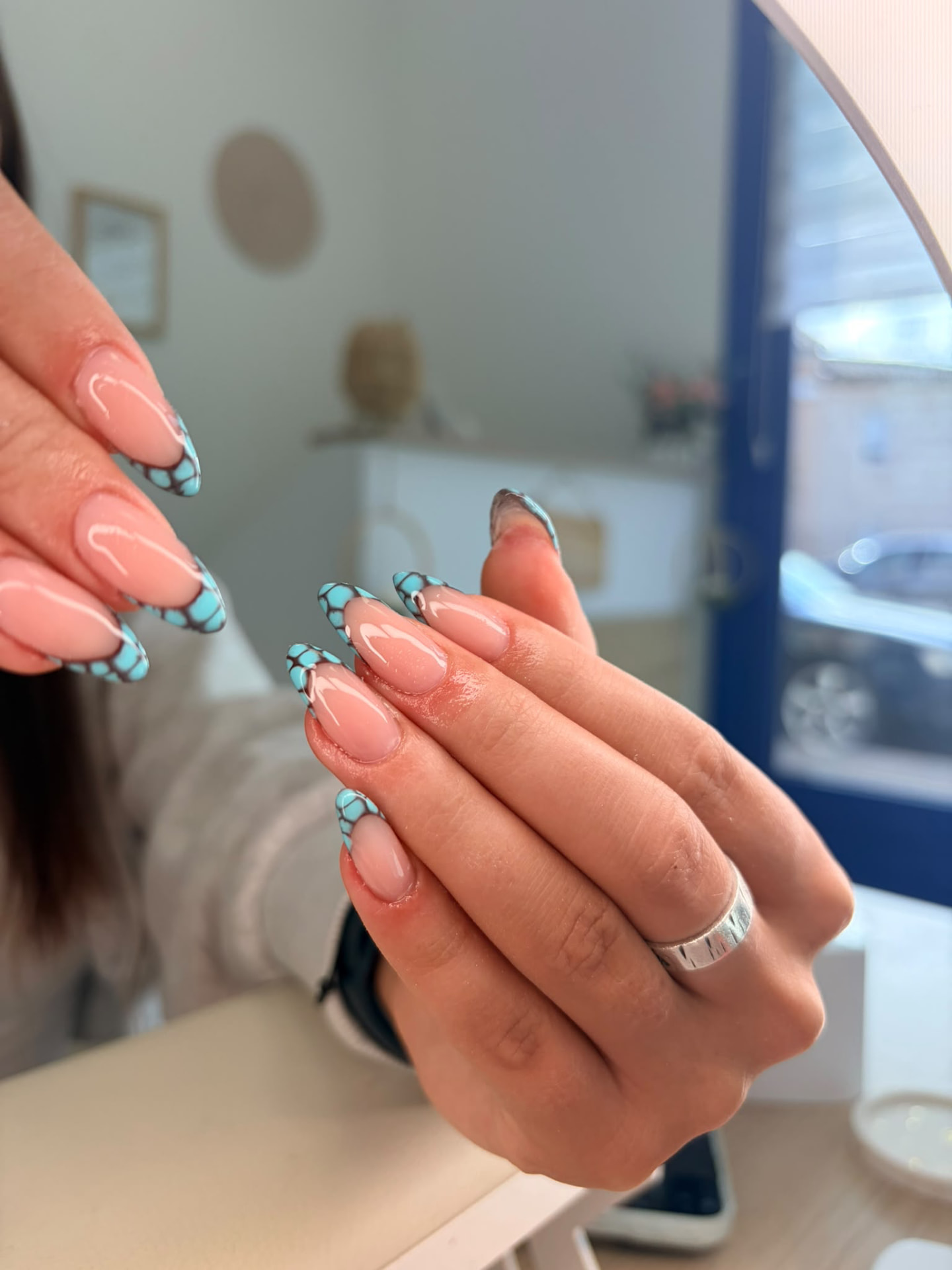 Nail art ongles amande, base nude et pointes turquoise à résille noire